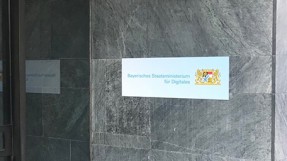 Aussenfassade des Digitalministeriums. Rechts im Bild ist ein Schild mit der Aufschrift Bayerisches Staatsministerium für Digitales zu sehen.